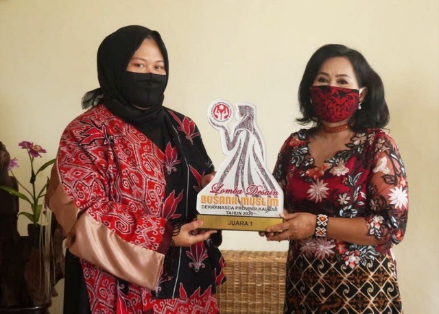 Sri Kurniawati saat menunjukan hadiah lomba desain yang diraihnya kepada Ketua Dekranasda Sanggau.