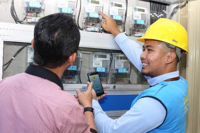 Petugas PLN sedang melakukan pencatatan meteran di rumah pelanggan.