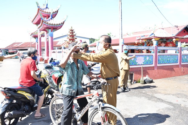 Kepala Dinas Kesehatan Kubu Raya saat memasangkan masker kepada masyarakat yang terjaring razia masker waktu lalu.