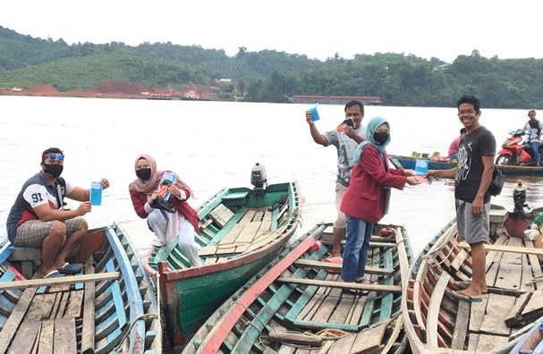 Mahasiswa Universitas Muhammadiyah Malang (UMM) saat membagikan masker gratis kepada ojek perahu.