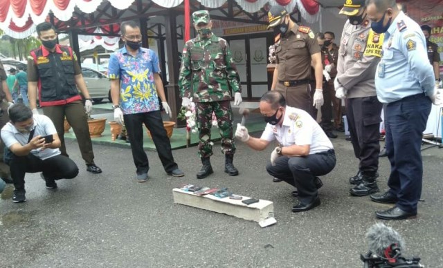 Wakil Bupati Sanggau, Yohanes Ontot saat memusnahkan barang dengan menggunakan palu.