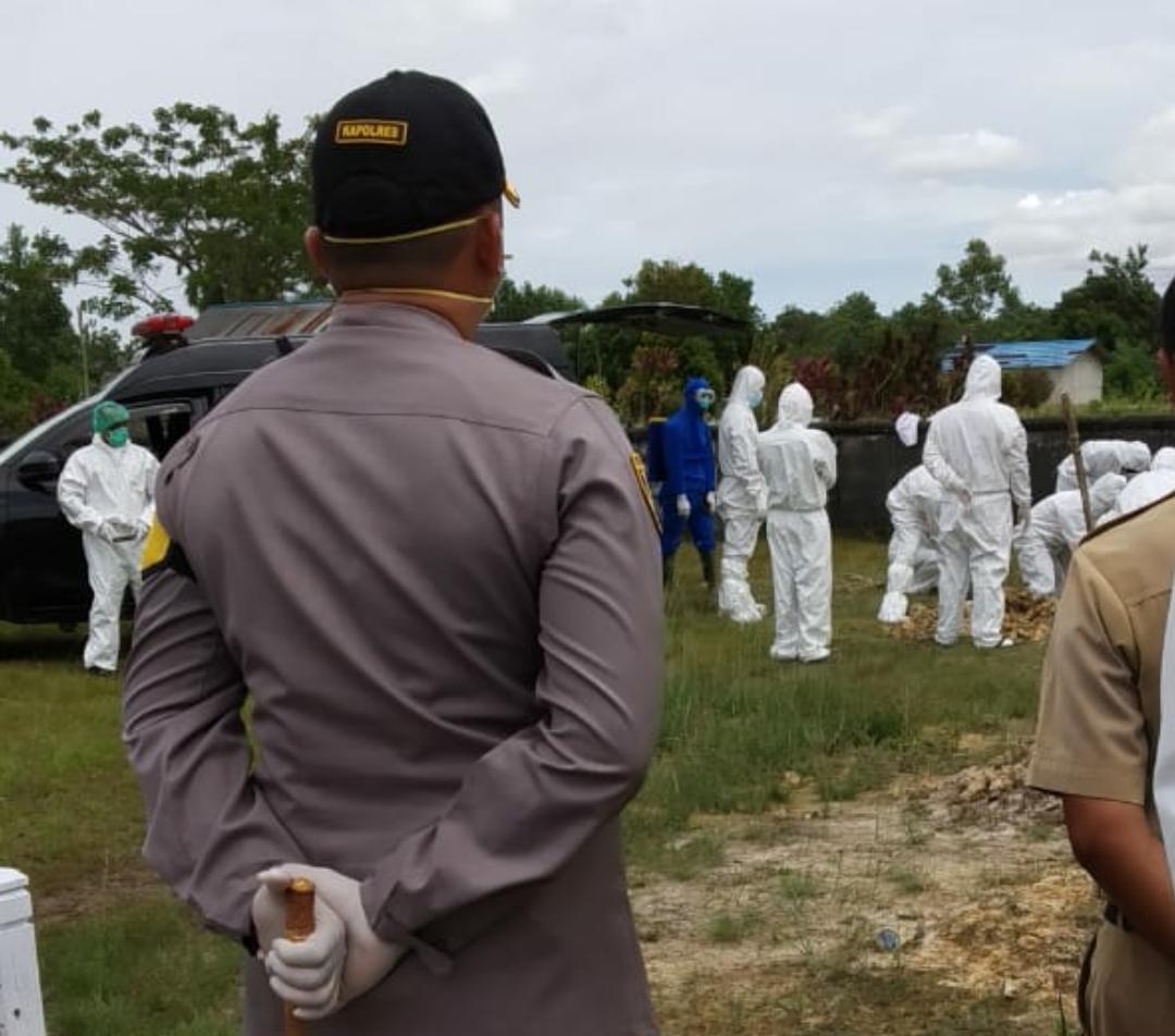 Petugas sedang melakukan pemakaman terhadap satu orang pasien yang meninggal dunia.