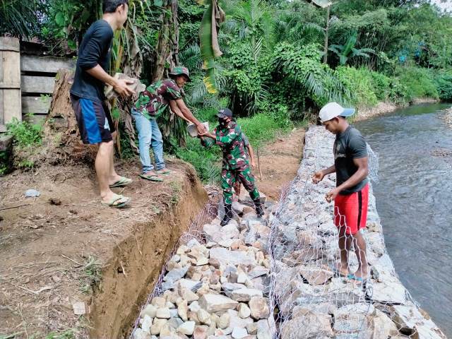 Satgas Pamtas RI–Malaysia Yonif 642 Kapuas gotong royong memasang dinding tanggul DAS di Dusun Bantan Desa Bungkang.