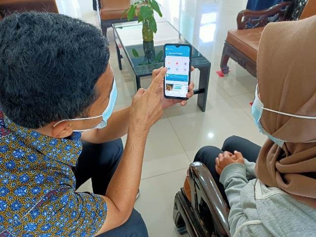 Salah seorang petugas sedang menjelaskan kepada pelanggan tentang aplikasi PLN Mobile