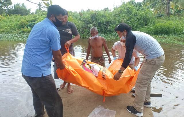 Personel kepolisian dibantu warga mengevakuasi jenazah Norma yang ditemukan di tepi parit di Desa Parit Keladi.