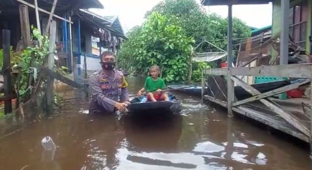 Kapolsek Sejangkung ikut membantu mengevakuasi warga dan anak-anak dengan menggunakan sampan lantaran ketinggian air mencapai pinggang orang dewasa.