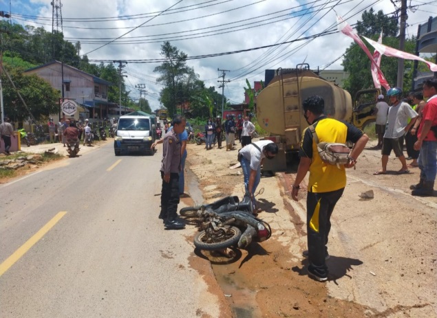 Petugas memeriksa kondisi sepeda motor yang tergeletak di jalan usai tabrakan dengan truk.