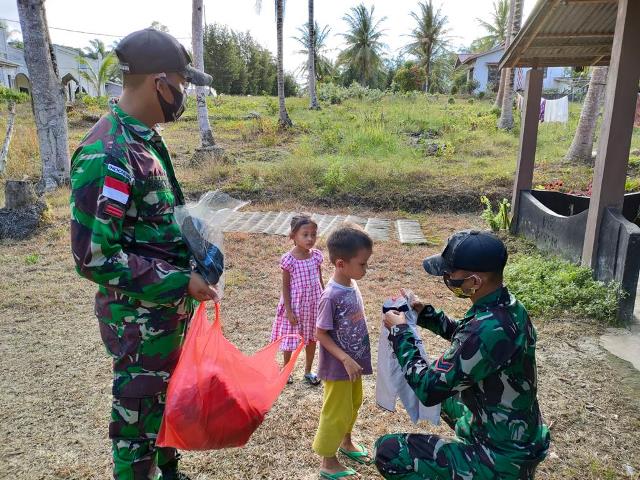 Personel Satgas Pamtas Yonif 642/Kapuas membagikan pakaian koko kepada anak-anak di Dusun Sempadan Kecamatan Paloh.