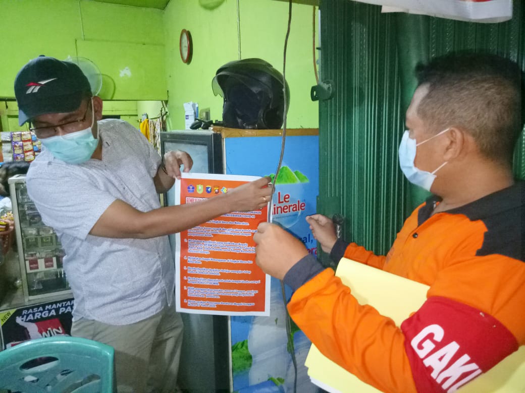Plt Kepala Dinas Kesehatan Sanggau saat memasang poster PPKM di sejumlah tempat usaha di Sanggau