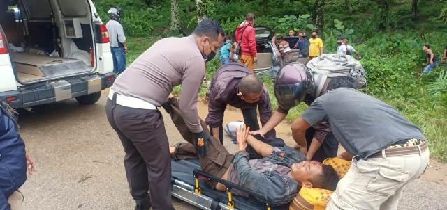 Warga dibantu petugas saat mengevakuasi korban dari dalam kendaraan yang ringsek usai menabrak pohon sawit, Minggu (6/6) pagi.