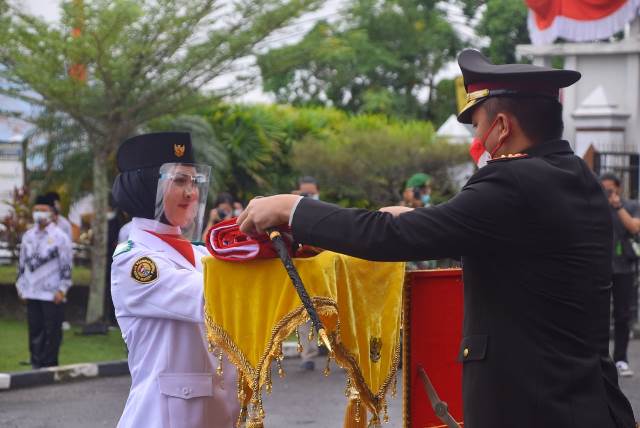 Kapolres Sintang menyerahkan bendera merah putih kepada petugas paskibraka yang akan mengibarkan merah putih saat upacara memperingati HUT ke-76 Kemerdekaan RI