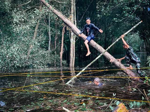 Personel TNI bersama warga bahu membahu membersihkan jalan akibat banjir.