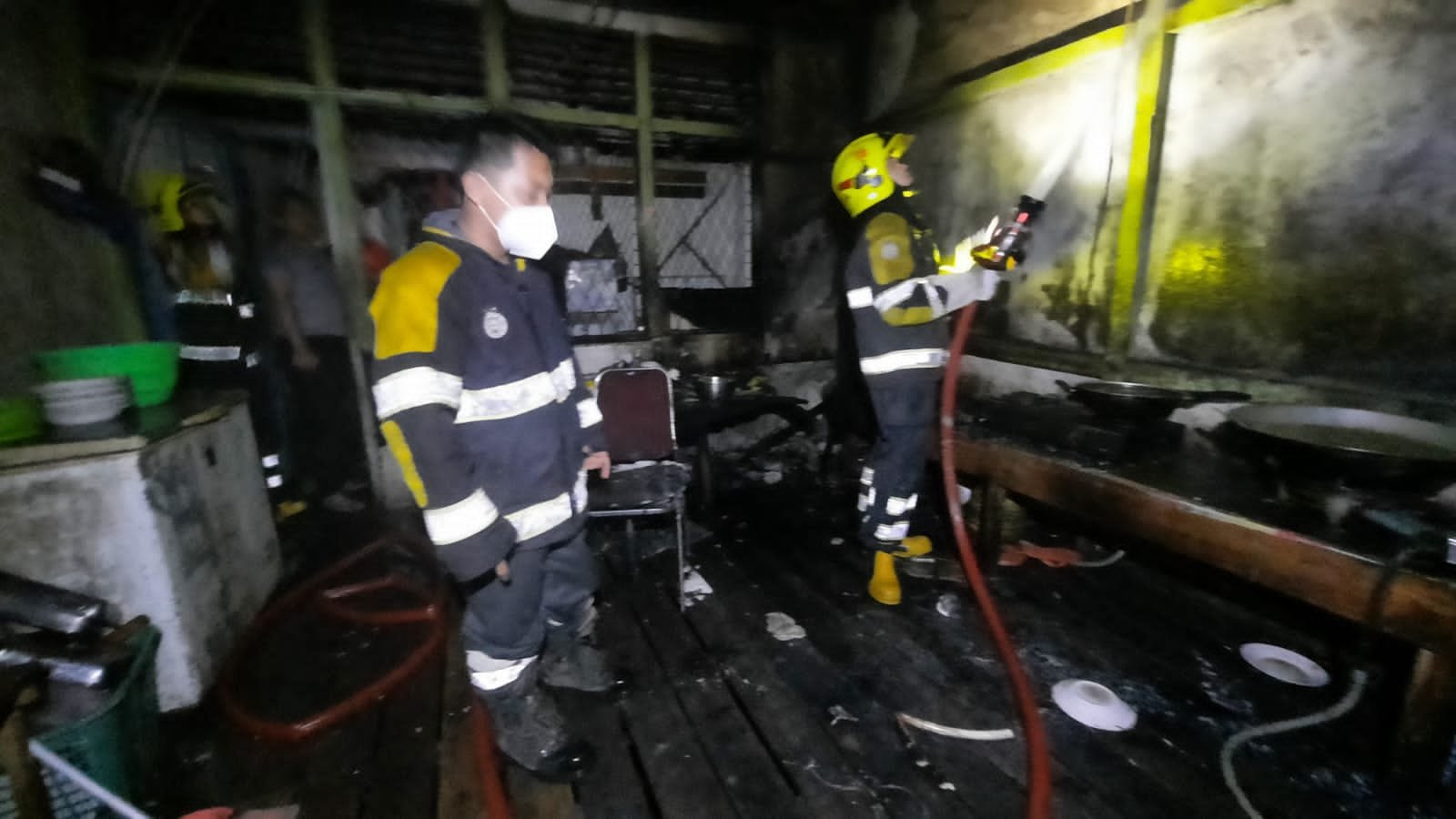 Petugas Damkar sedang berupaya memadamkan api yang nyaris melahap rumah makan.