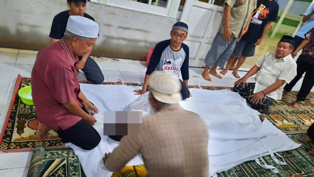 Warga akan melakukan salat jenazah terhadap korban yang ditemukan terendam banjir di rumahnya