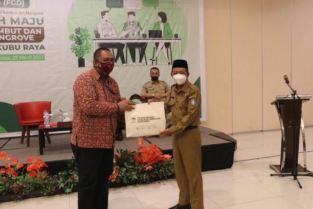 Koordinator Paket kerja pengelolaan pengetahuan, proyek Peat-IMPACTS, ICRAF Indonesia menyerahkan buku pedoman tentang gambut kepada Kepala Dikbud Kubu Raya.
