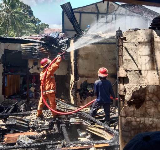 Petugas Damkar memadampkan api rumah yang terbakar di Sui Batu ludes terbakar dikarenakan arus pendek listrik.