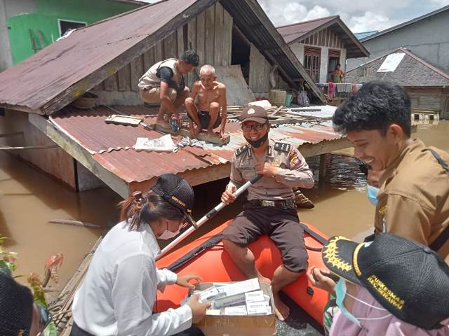 Petugas sedang membantu warga di Kecamatan Serawai yang berada di atas atap rumah lantaran rumahnya terendam banjir sejak dua hari terakhir.