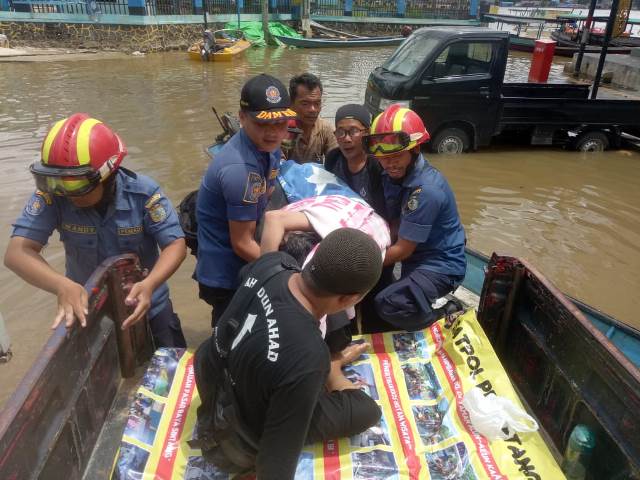 Petugas saat membantu mengevakuasi korban banjir yang menginggal dunia di Sintang.