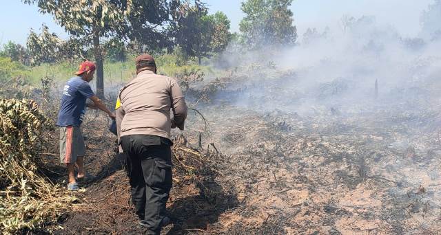 Personel Polsek Batu Ampar dibantu masyarakat seadng memadamkan api yang membakar lahan. Karhutla ini terdeteksi melalui aplikasi lancang kuning.