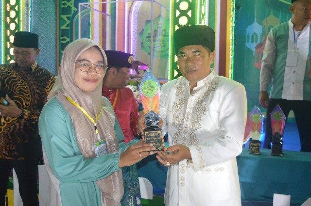 Wakil Ketua DPRD Kubu Raya Suharso saat menyerahkan tropi kepada kafilah yang meraih juara di MTQ IX yang berlangsung di Kecamatan Sui Kakap pada Kamis (22/6) malam. Dan untuk selanjutnya Kubu tuan rumah MTQ X tahun 2024. Foto: dian