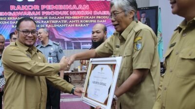Pj Sekda Kalbar, Muhammad Bari menyerahkan penghargaan kepada tiga kepala daerah di Kalbar yang meraih nilai tertinggi RANHAM saat rakor Penyusunan Laporan Akhir dan Rekomendasi Pembinaan dan Pengawasan Produk Hukum Daerah, Selasa (24/10). Foto: tmB