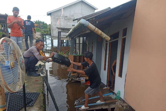 Bhabinkamtibmas Desa Kuala Dua sedang membantu evakuasi barang rumah warga yang roboh akibat abrasi di Dusun Keramat I Desa Kuala Dua lantaran curah hujan yang tinggi, Jumat (12/1)