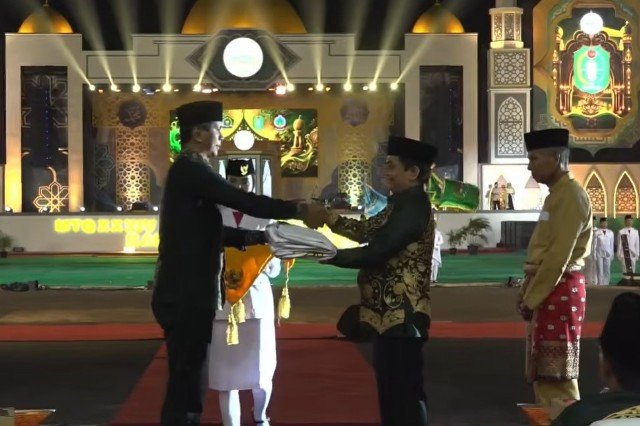 Penyerahan bendera Musabaqah Tilawatil Quran (MTQ) oleh Gubernur Kalbar Ria Norsan yang diwakili Staf Ahli Gubernur Kalbar Bidang Sosial dan Sumber Daya Manusia (SDM), Sefpri Kurniadi kepada Wakil Wali kota Pontianak, Bahasan saat malam penutupan MTQ XXXIV Tahun 2026 di Kayong Utara, Sabtu (8/8/2026). Foto: ist/berkatnewstv